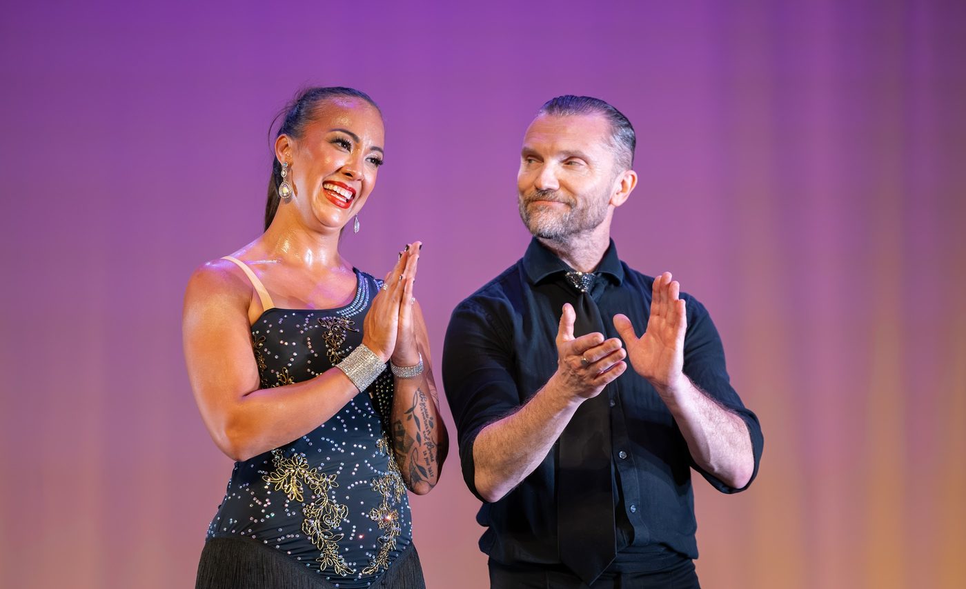 Two dancers applauding the audience on stage at the close of a routine.
