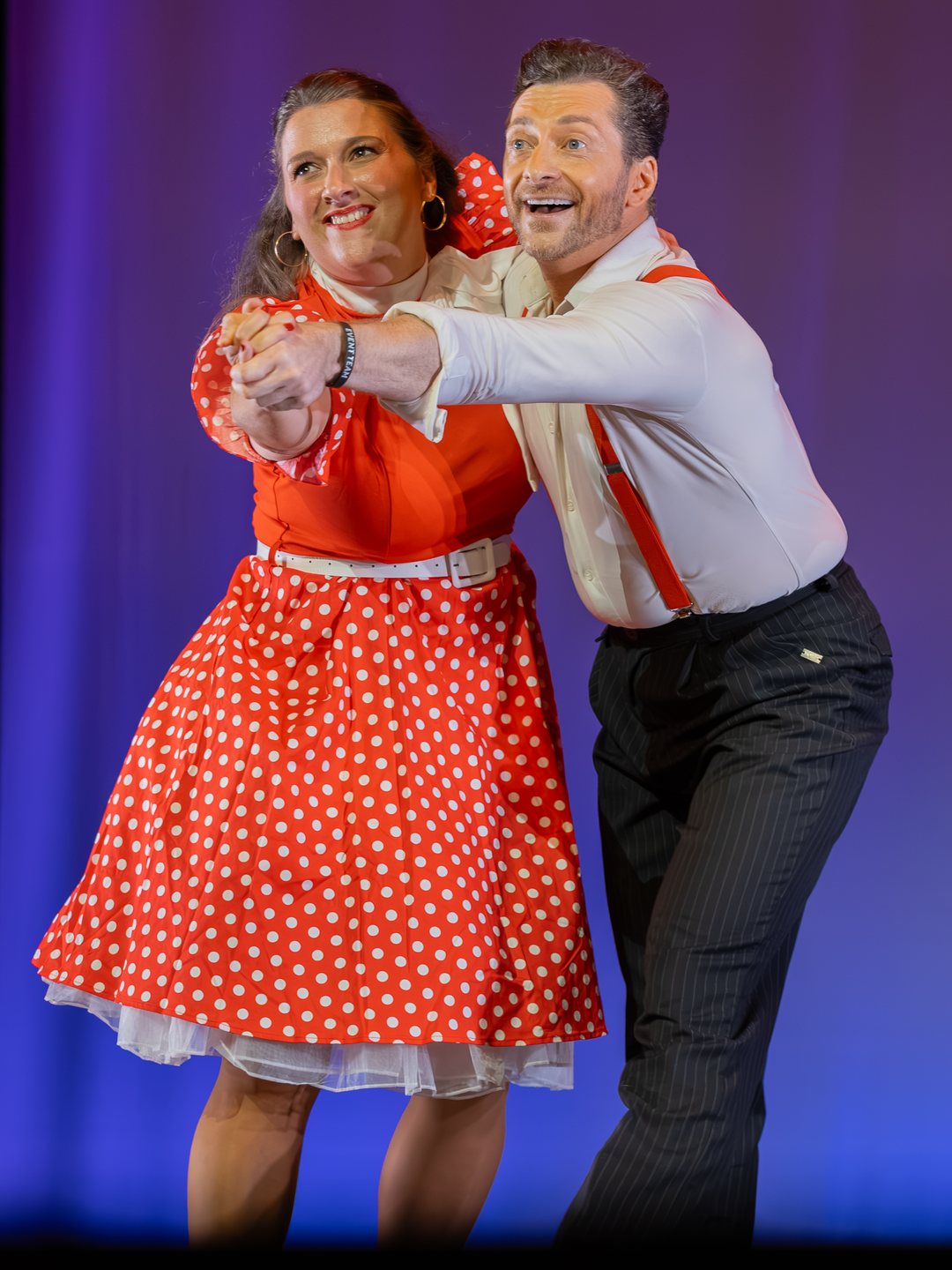 A local celebrity in a red polka-dot dress dancing with her Arthur Murray partner on the Lewis Auditorium stage.